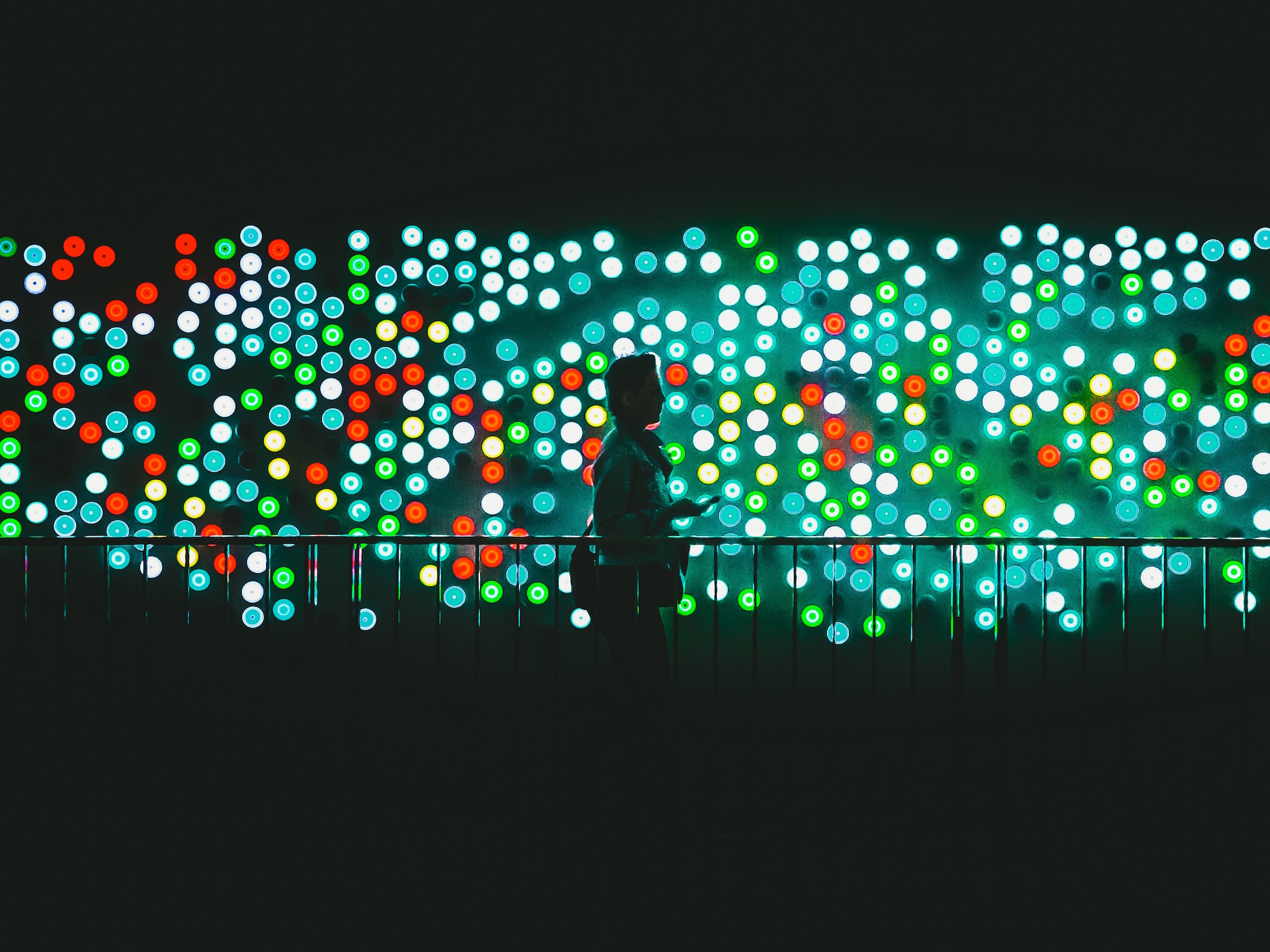 man walking in front of a wall of light dots