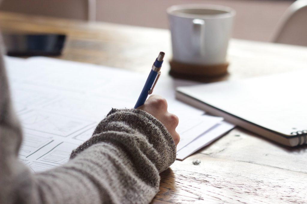 decorative image: person writing at desk