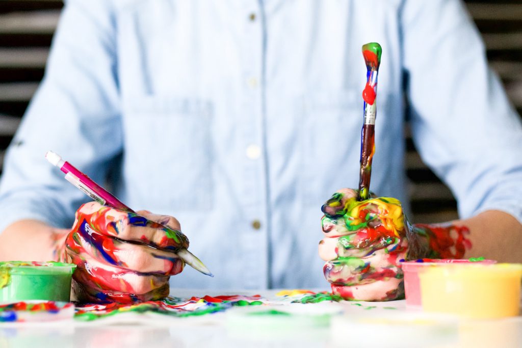 decorative image: person painting with pen and brush in hand