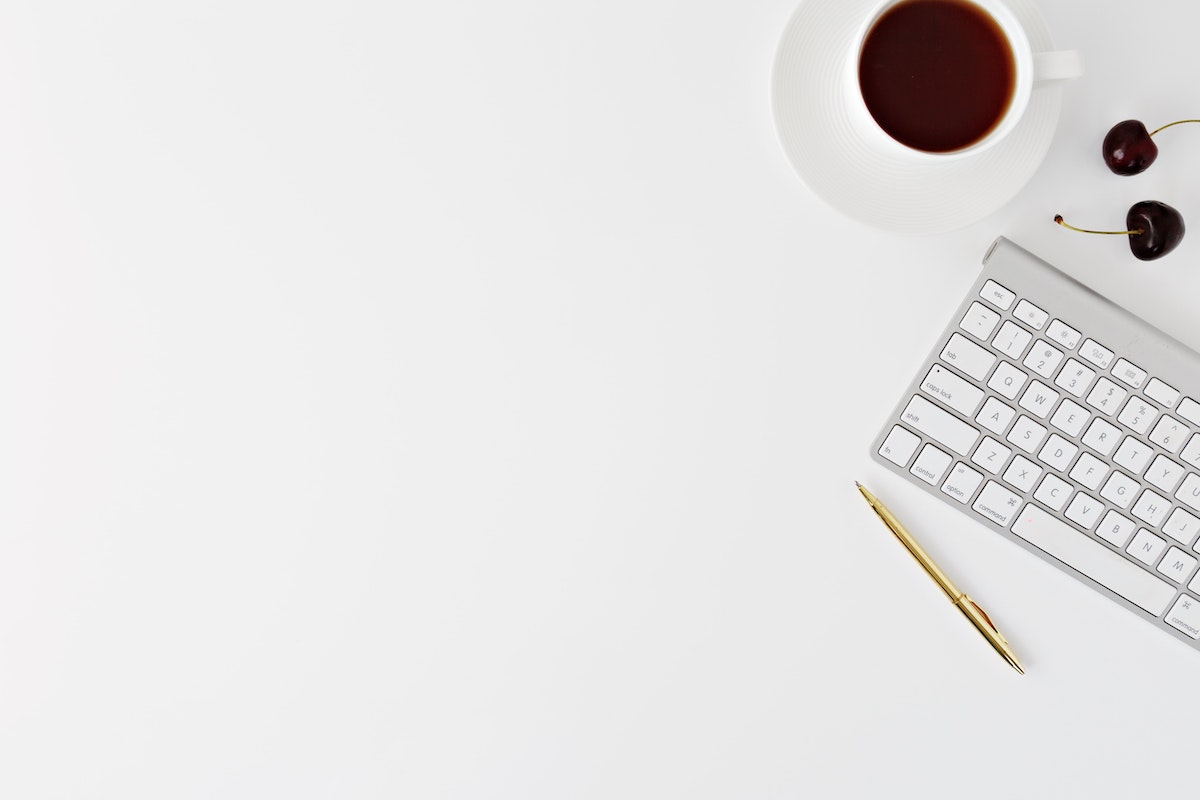 computer keyboard, cherries, pen, and coffee on white background. 